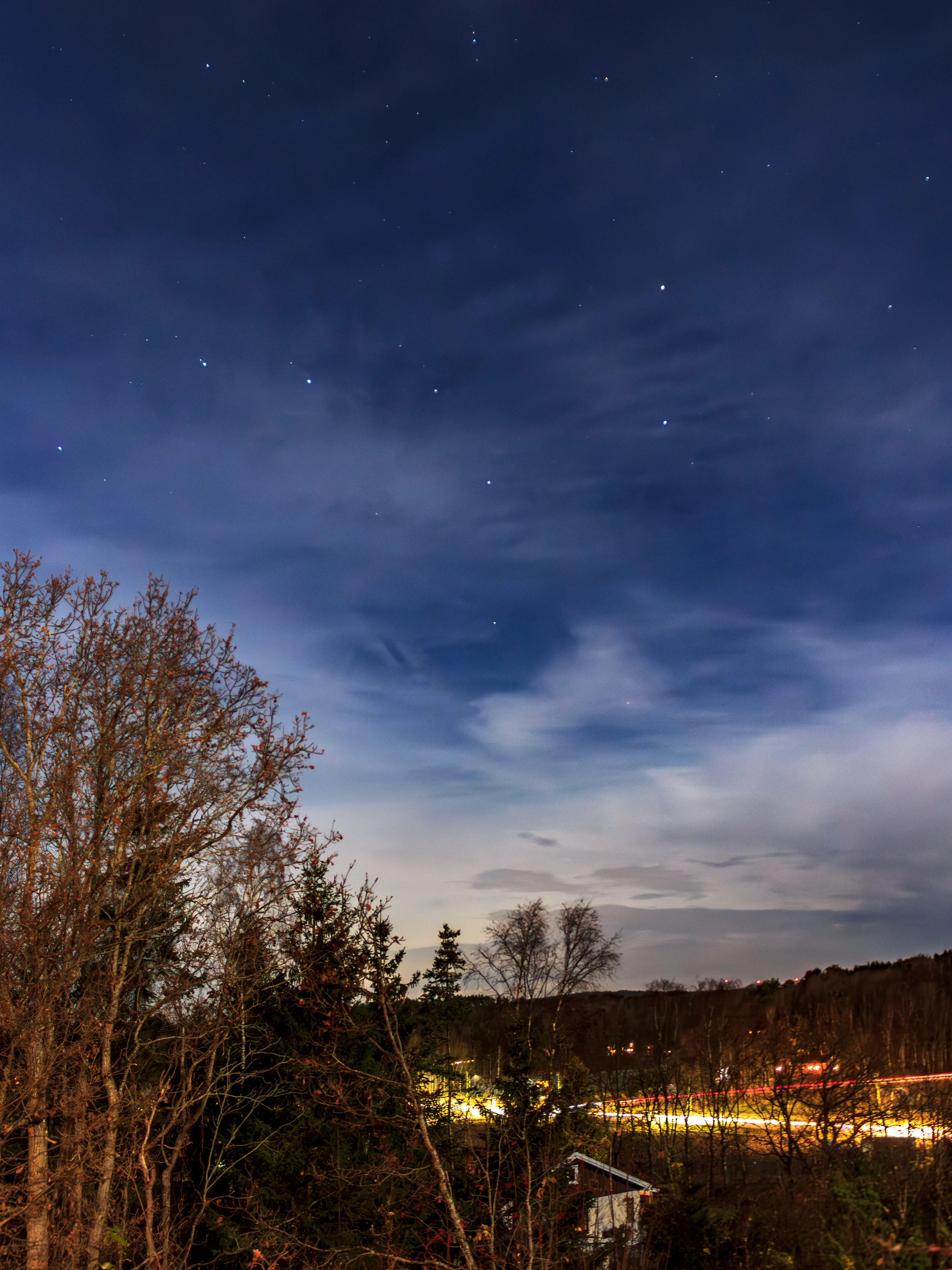 The Big Dipper asterism above trees at night, with thin clouds, over Brastad, Sweden
