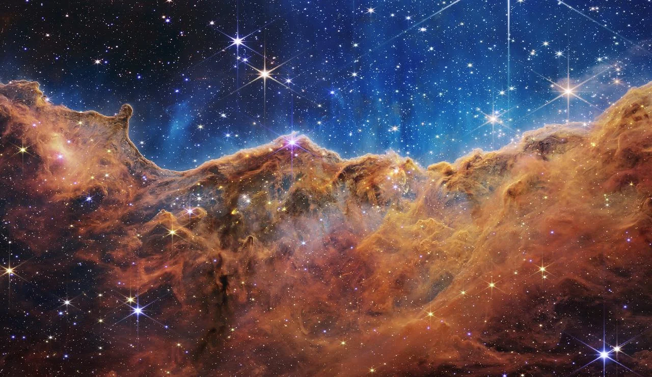 JWST near-infrared image of the Cosmic Cliffs in the Carina Nebula, showing towering pillars of gas and dust backlit by young stars