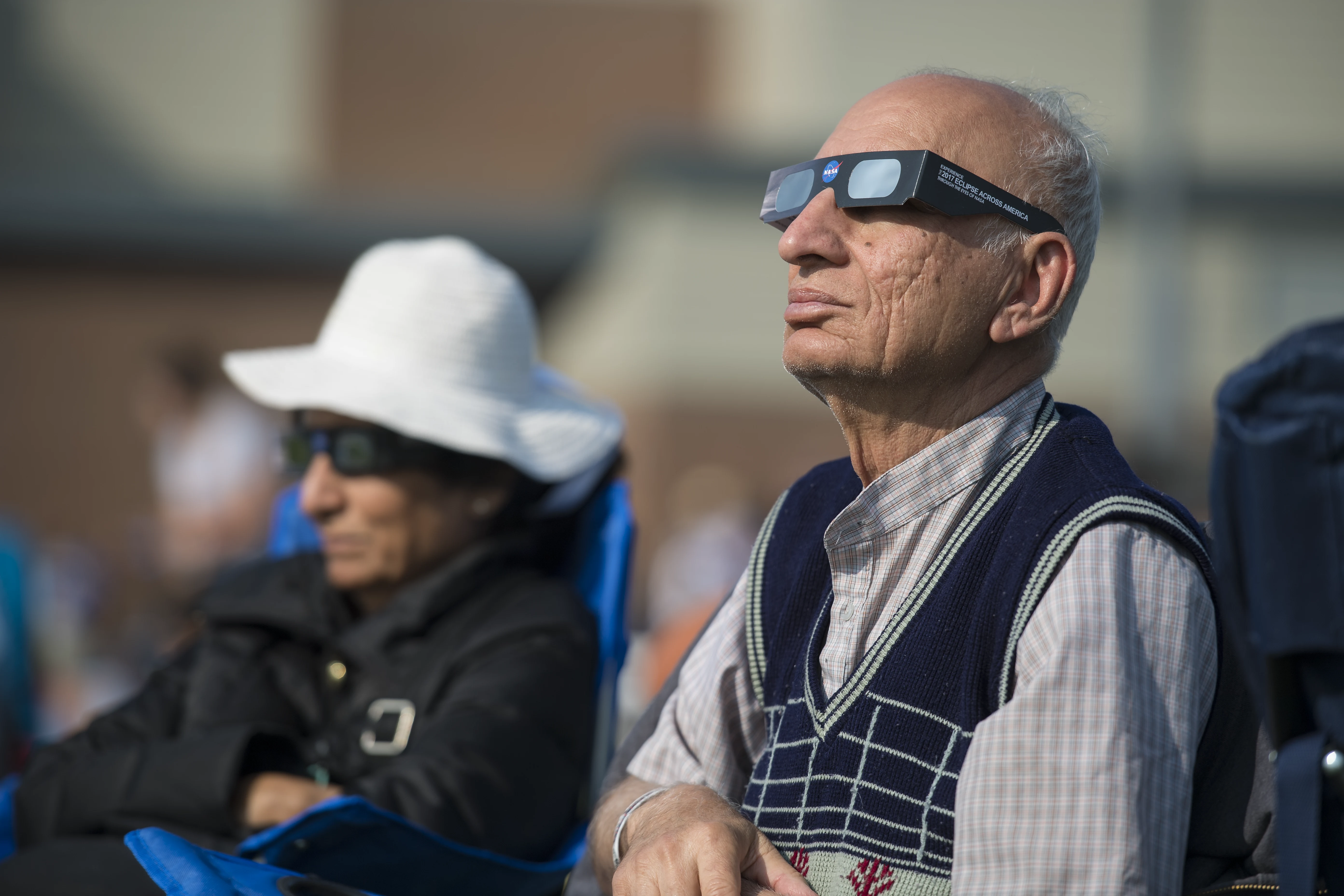 A man and a woman watch the 2017 total solar eclipse through cardboard eclipse glasses in Madras, Oregon