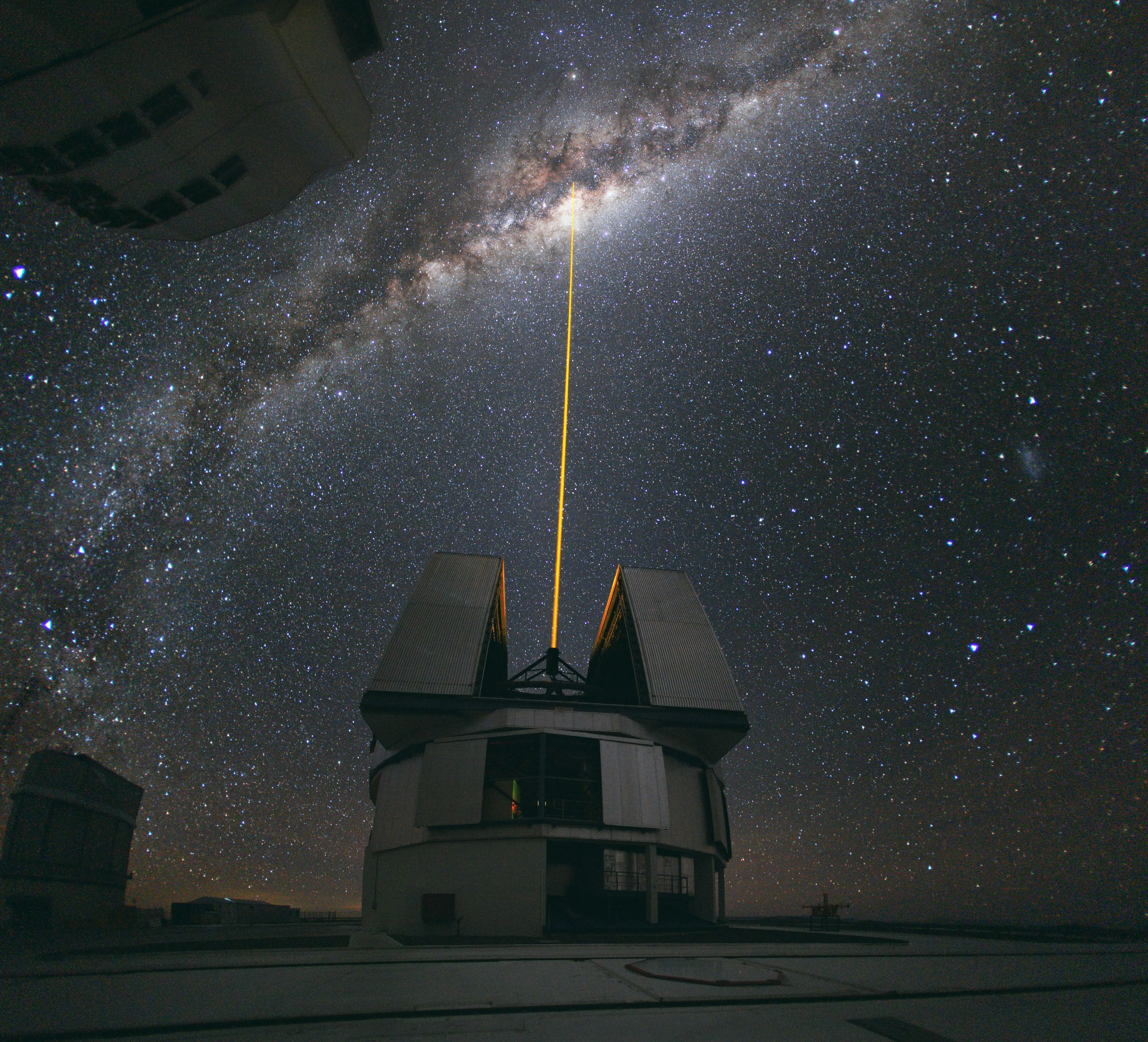 A green laser beam from the Very Large Telescope at ESO's Paranal Observatory in the Atacama Desert points up into the arch of the Milky Way over the southern night sky.