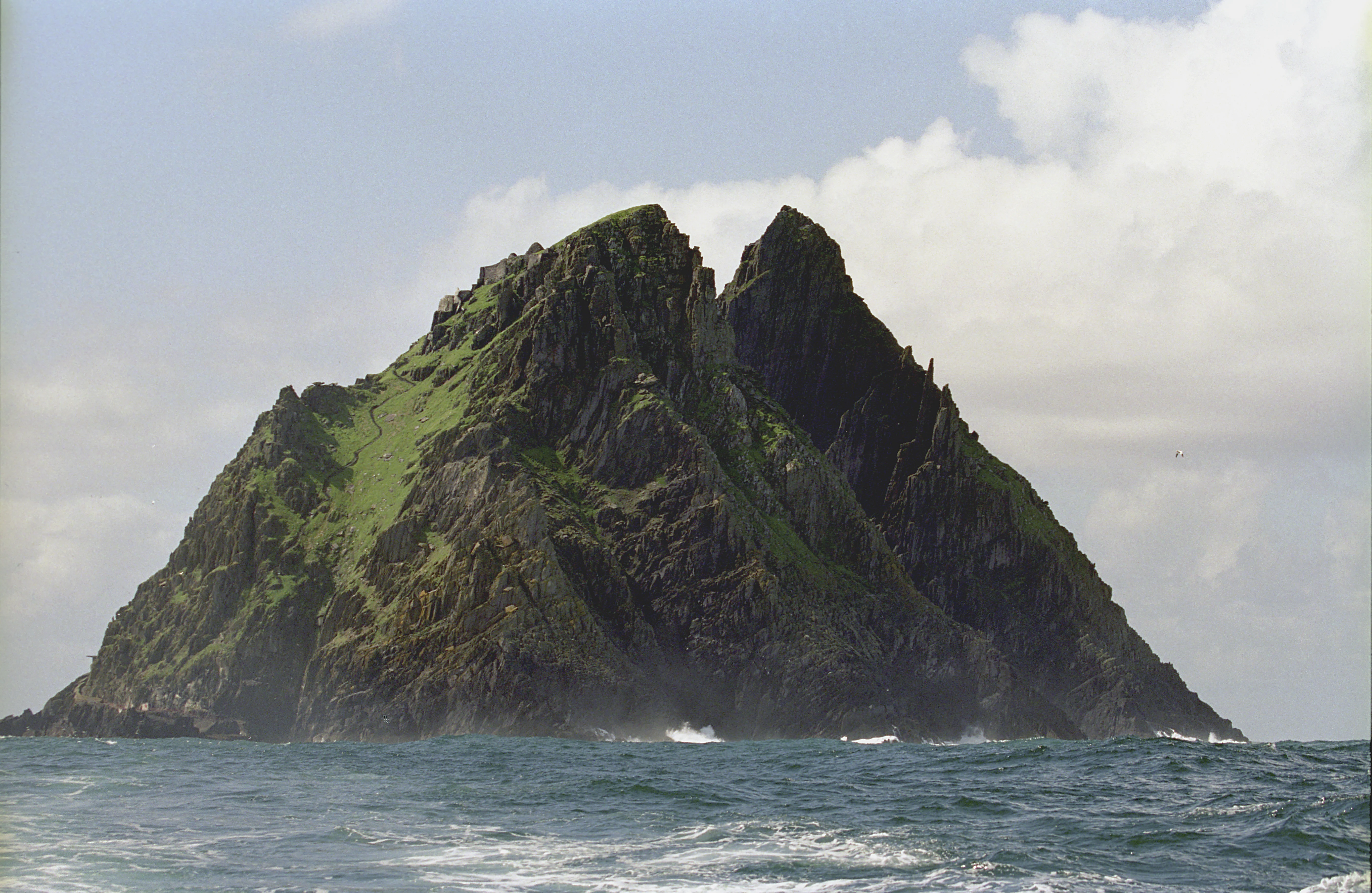 The twin-peaked island of Skellig Michael rising steeply from the Atlantic off the Iveragh Peninsula in County Kerry, with waves breaking at its base