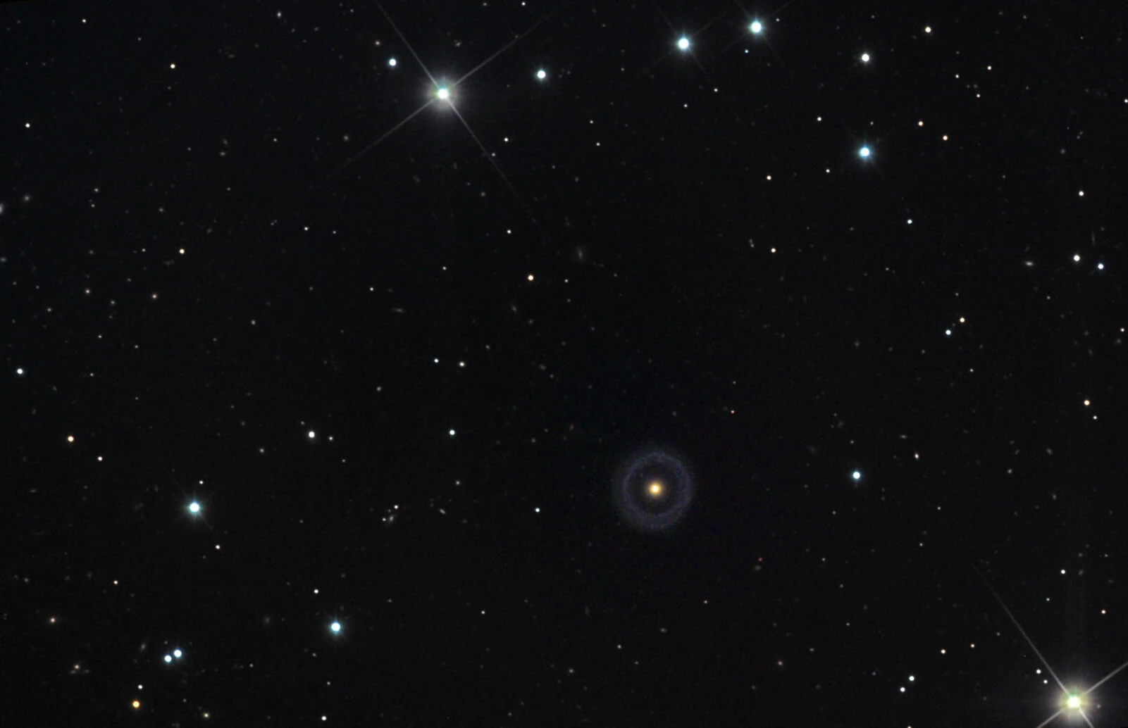 Hoag's Object, a ring galaxy: a bright yellow-white core encircled by a detached blue ring of young stars, with a smaller ring galaxy visible through the gap.