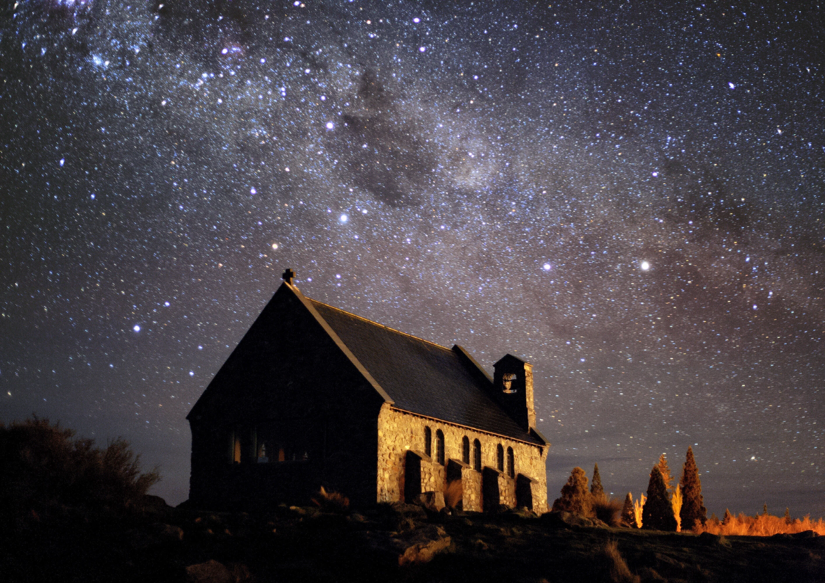 The stone Church of the Good Shepherd on the shore of Lake Tekapo, silhouetted under the Milky Way and Southern Cross in New Zealand's Aoraki Mackenzie Dark Sky Reserve.