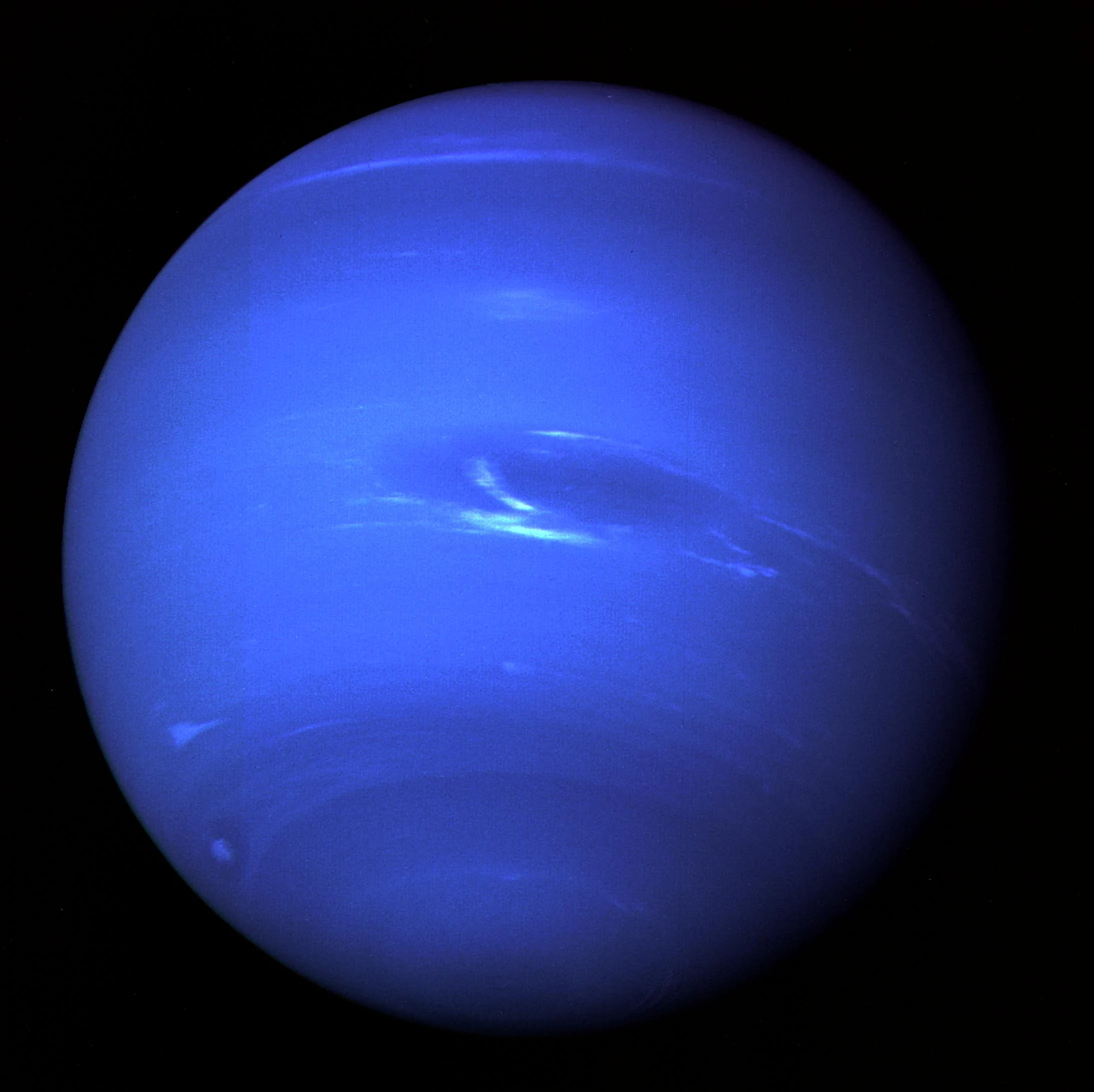 Neptune imaged by NASA's Voyager 2 in 1989 — a deep-blue disc marked by the dark oval of the Great Dark Spot and streaks of white, high-altitude methane-ice cloud.